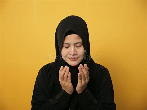 Portrait Of Masian Muslim Woman Prays To God Praying Gesture Hands Raised Up Against Yellow