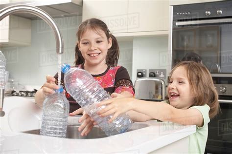Girls Filling Up Water Bottle In Kitchen Stock Photo Dissolve
