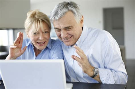 Happy Senior Loving Couple Relaxing With Laptop Computer At Park
