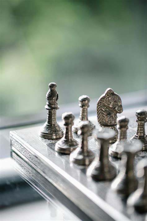 Metal Chess Pieces On Board In Room · Free Stock Photo