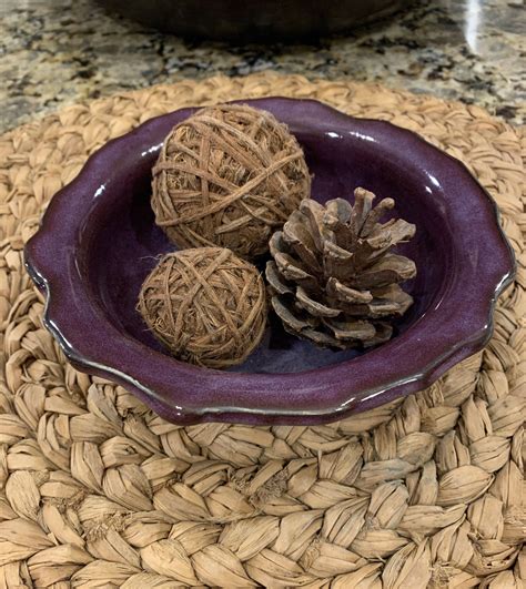 Three Balls Of Twine Are In A Purple Bowl On A Woven Place Mat Next To