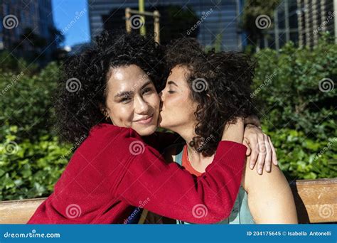 Pareja De Lesbianas Sonrientes Que Abrazan Y Que Se Relajan En Un Banco Del Parque Imagen De