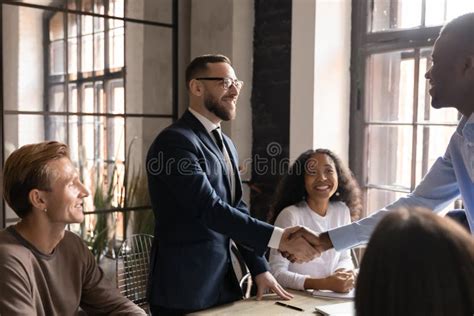 Smiling Businessman Wearing Glasses Shaking Hands With Diverse Business Partner Stock Image