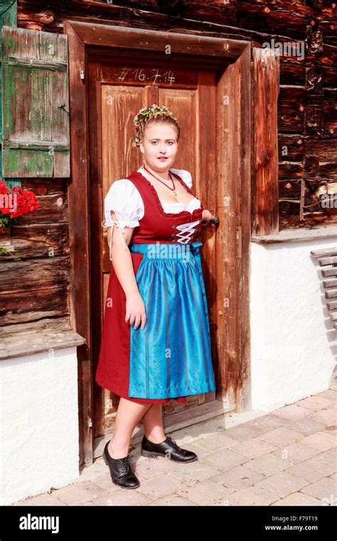 Young Chubby Bavarian Woman In Traditional Dirndl Before An Old