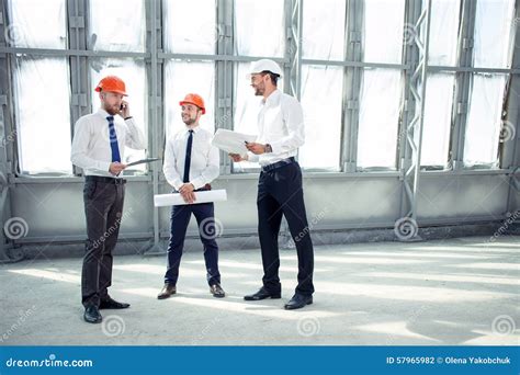 Cheerful Young Builders Are Discussing The Plan Of Stock Photo Image
