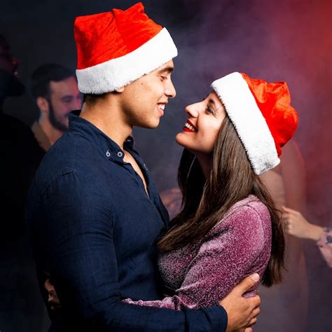pareja abrazada con sombreros de navidad foto gratis
