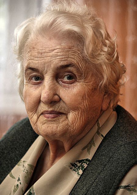 an older woman with white hair and blue eyes looking at the camera while wearing a scarf
