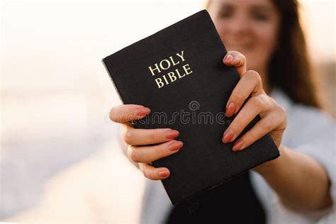 christian woman holds bible in her hands reading the holy bible on the sea during beautiful