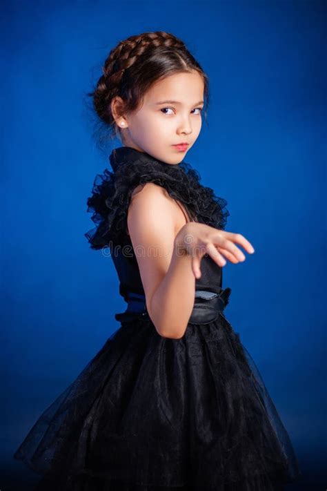 Little Girl In A Black Dress With A Pigtail Hairstyle On Her Head Poses