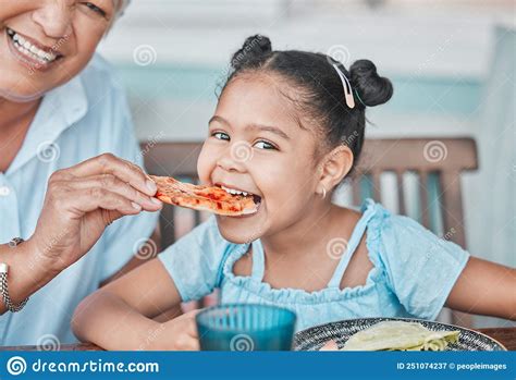 Shes A Bit Impatient Shot Of A Mature Woman Feeding Her Granddaughter Pizza While Having Lunch