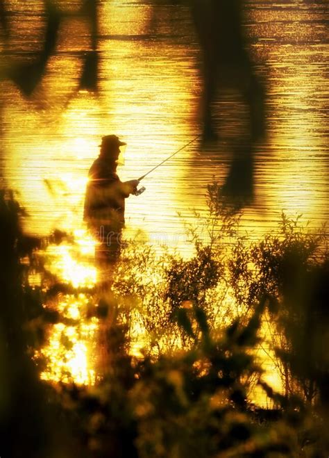 Silhouette Of Fisherman In Water Captured At Sunset With Light