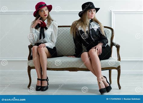 Two Beautiful Women In Beautiful Dresses Sitting On Sofa Stock Image