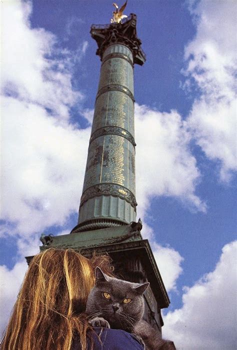 A Woman And Her Cat Standing In Front Of A Tall Tower With A Statue On Top