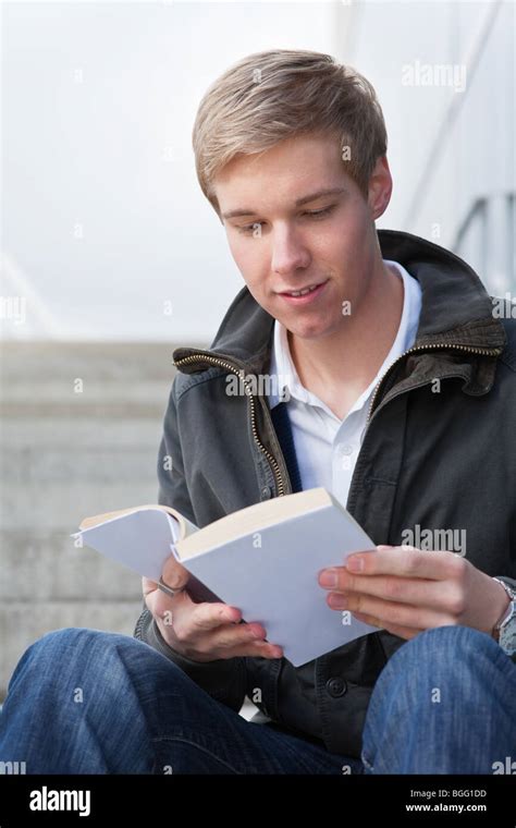 Young Cheerful Handsome Guy Reading A Book With Blank Cover Stock Photo