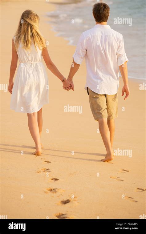 Romantic Couple Holding Hands Walking On Beach At Sunset Man And Woman In Love Footprints In