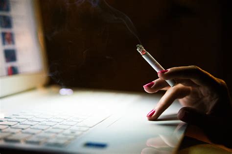 Business Woman Smoking Cigarette While Working On Laptop At Nigh Stock