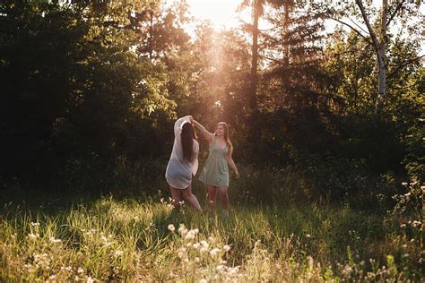 happy lesbian couple dancing in forest during summer photograph by cavan images fine art america