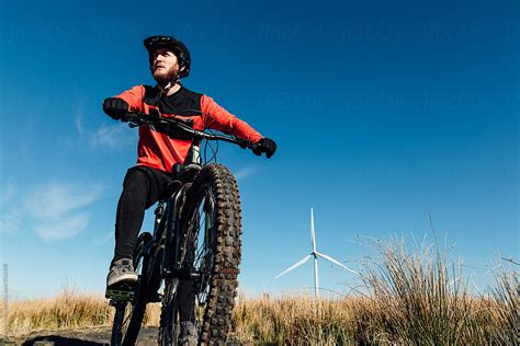 A Man In A Red And Black Jersey On A Mountain Bike At A Wind Farm In Scotland By Stocksy