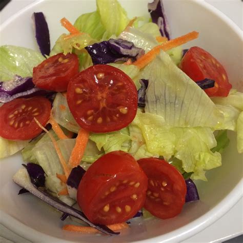 A White Bowl Filled With Lettuce And Tomatoes