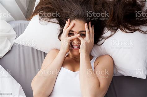 Beautiful Young Caucasian Smiling Woman Covering Her Eyes On Bed Stock