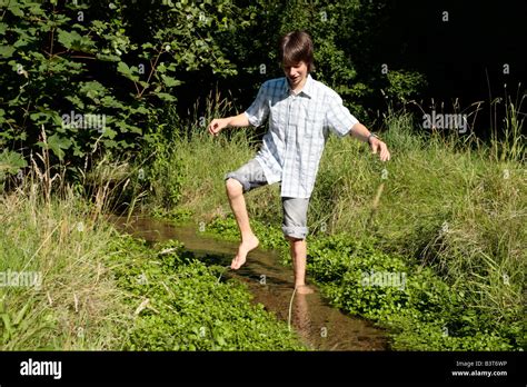 Teenage Boy Walking Barefoot Across A Stream Stock Photo Alamy