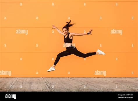 positive lively vivid girl with fit body in tight sportswear jumping running and smiling full