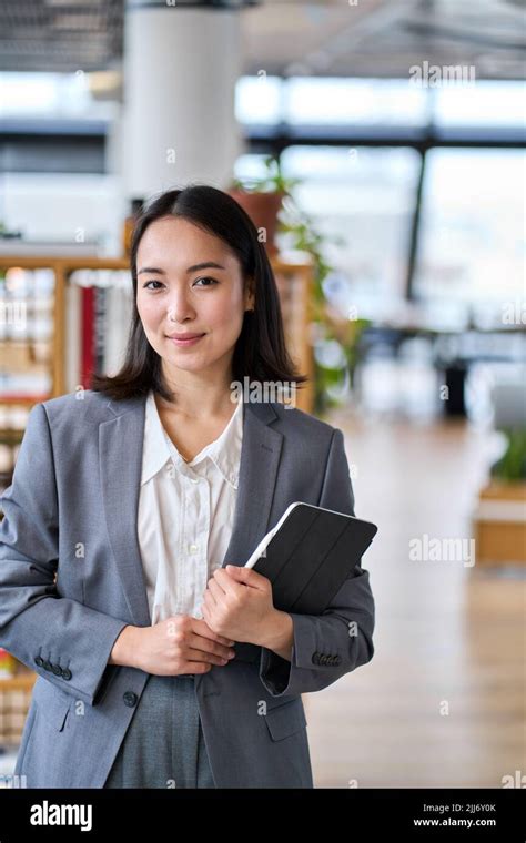 Smiling Young Asian Business Woman Standing In Office Vertical