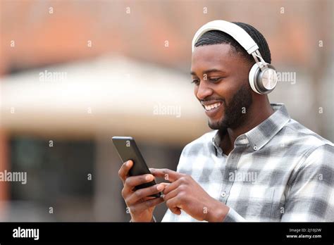 Happy Man With Black Skin Wearing Headphones Walking In The Street