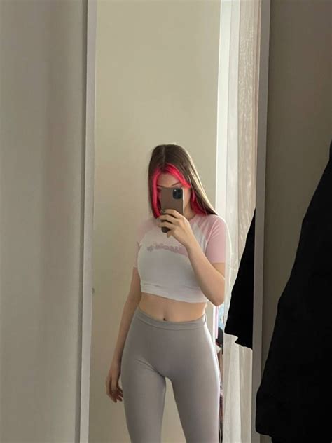 A Woman Taking A Selfie In The Mirror Wearing Leggings And Sports Bra