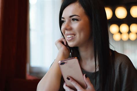 Portrait Of A Smiling Beautiful Girl With Dimples On The Cheeks In A Cozy Café Against The