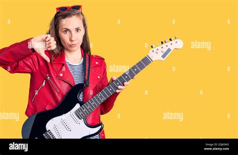 Young Beautiful Blonde Woman Playing Electric Guitar With Angry Face