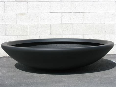 A Large Black Bowl Sitting On Top Of A Cement Floor