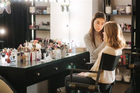 Beautiful Female Makeup Artist Doing Makeup For A Young Blond Hair Girl In A Beauty Salon