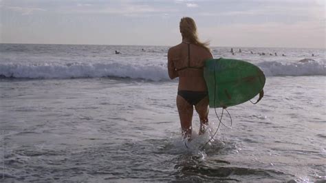 Female Surfer Is Walking Into The Water With Surfboard Slow Motion By Stocksy Contributor