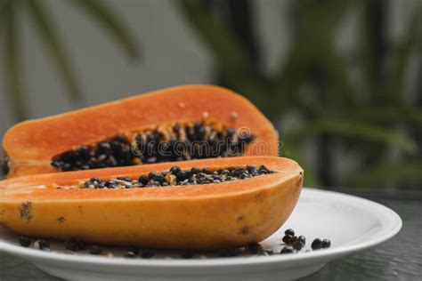 Half Of Ripe Papaya With Seed On A White Plates And With A Green Plants