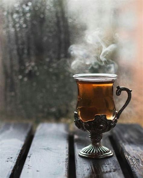 A Cup Of Tea Sitting On Top Of A Wooden Table Next To A Glass Window