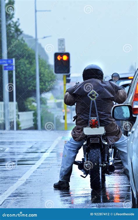 Motorcycle Biker Riding In Rain In Morning City Traffic Stock Photo