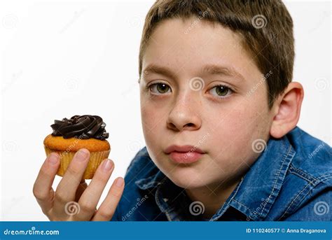Young Boy With Denim Shirt Eating Chocolate Cupcake On White Isolated