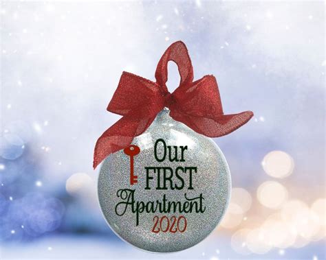 A Glass Ornament With The Words Our First Apartment 2020 Hanging From A