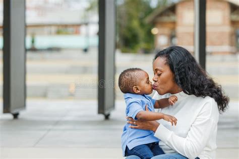 A Beautiful African American Mom Giving Her Toddler Son A Kiss Stock