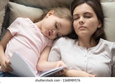 Tired Mother Sleeps While Her Daughter Stock Photo