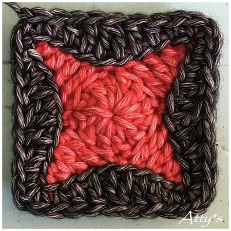 A Crocheted Square With A Red Star In The Center And Black Squares