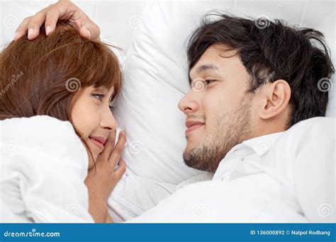 Young Couple In Love Looking At Each Other Lying Together On White Bed Romantic Moment In