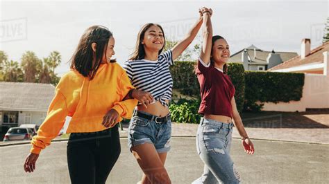Three Teenage Girls Walking On Street Holding Their Hands Smiling Teenage Girls Friends Walking