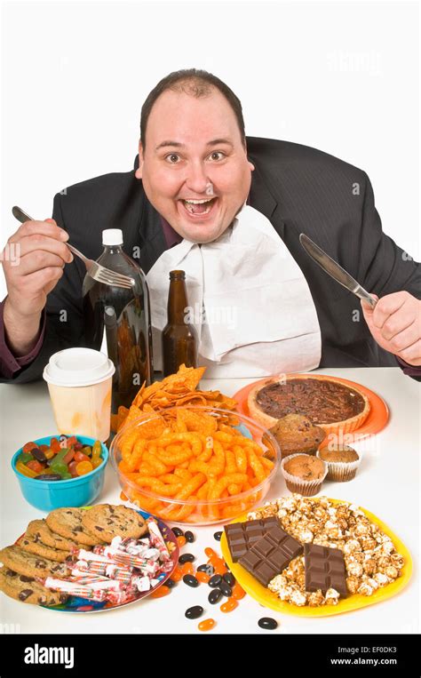 Overweight Man Sitting At A Table Full Of Junk Food Stock Photo Alamy