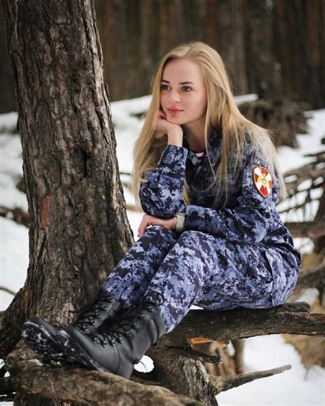 a woman sitting on top of a tree branch in the snow with her hand under her chin