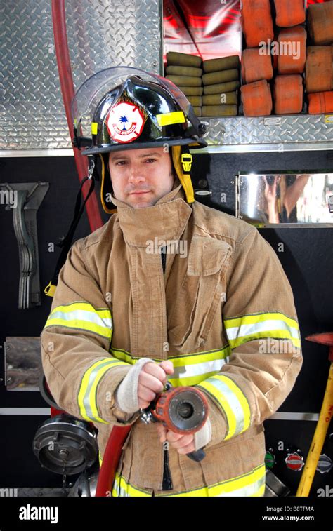 Male Firefighter Holding Fire Hose In Front Of Fire Truck Wearing Stock