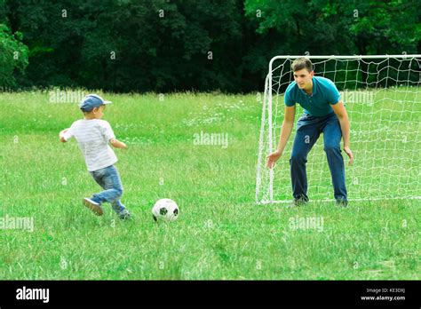 Padre E Hijo Jugando Al Fútbol En Un Césped Verde En El Parque