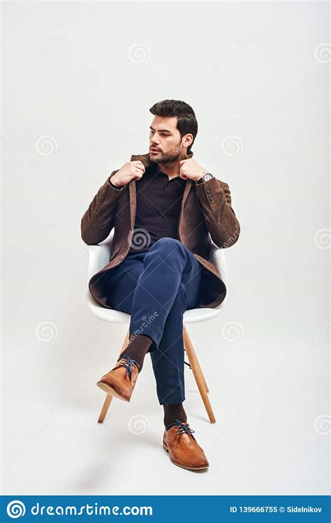 Confident In His Style Stylish Dark Haired Man Sitting On A Chair