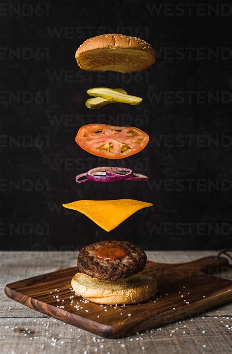 Burger With Floating Separated Ingredients On Black Background Stock Photo